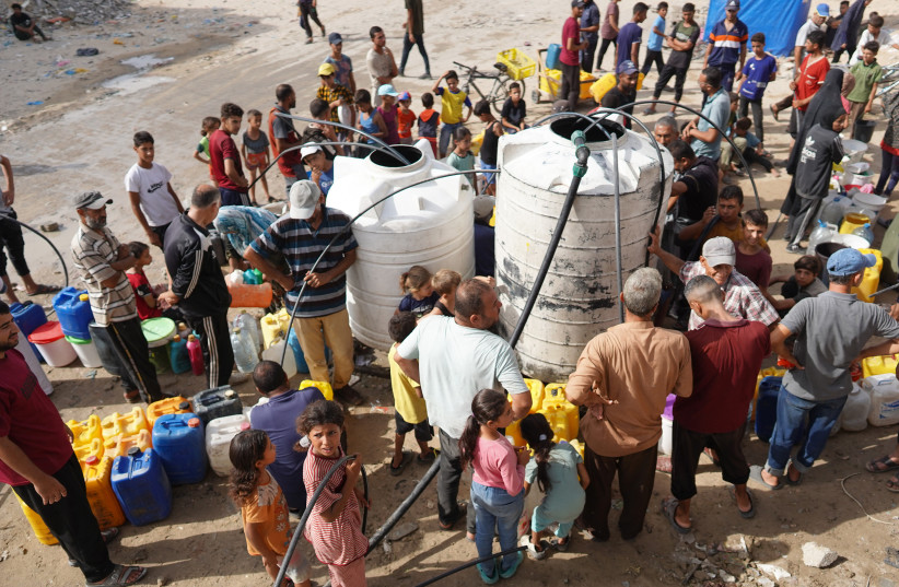 Palestinos se reúnem em torno de dois grandes reservatórios de água enquanto transferem água para recipientes menores em um bairro residencial da cidade de Khan Yunis, no sul da Faixa de Gaza, em 5 de julho de 2024.